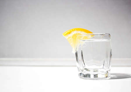 A glass of alcohol with a lemon for a snackの写真素材