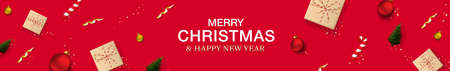 Merry Christmas and New Year horizontal banner. Red background with realistic gift boxes in craft paper, Christmas balls, christmas tree, candy and golden confetti. Header for website.のイラスト素材