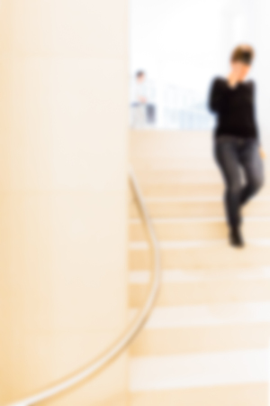 Woman in Museum climbing a flight of stairs, man stands up, defocusedの写真素材