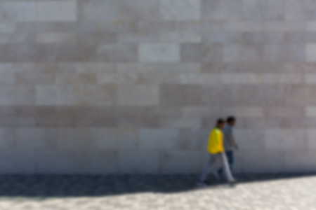 Two men in front of stone wall on sidewalk, defocusedの写真素材