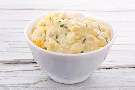 potato salad in white bowl on white wooden backgroundの写真素材