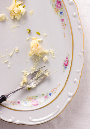 Scraps of cake on almost empty plate with a fork - top viewの写真素材