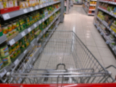 Out of focus shopping cart in supermarket aisle between shelves.の写真素材