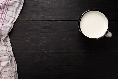Black weathered wooden board with white tin cup with milk as image background with copy-space.の写真素材