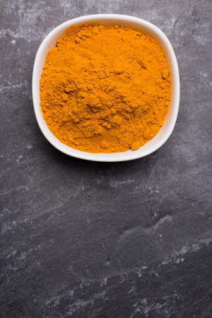 Kurkuma in white bowl on slate background, view from above.の写真素材