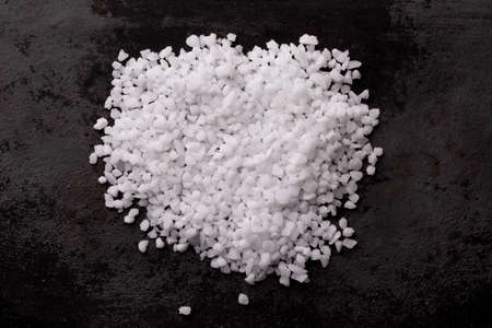 Heap of salt on black background, view from above, closeup.