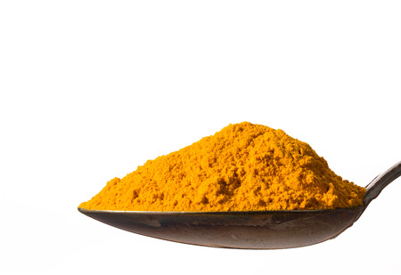 Heap of kurkuma powder on spoon, isolated on white background, closeup.の写真素材