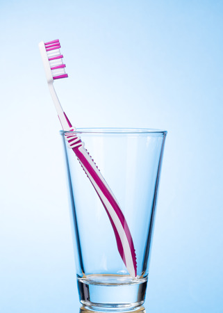Single toothbrush in glass on light blue backgroundの写真素材