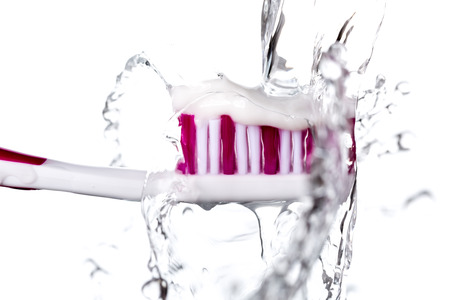 Toothbrush with toothpaste under splashing water isolated on white background, closeup.の写真素材