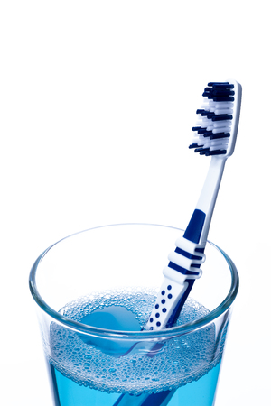 Toothbrush in glass with mouth rinse isolated on white, closeup.の写真素材