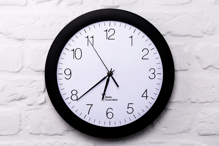 Wall clock on white brick wall, full frame, closeup