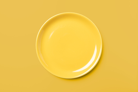 Yellow pastel plate on same colored background, pop art syle, view directly from aboveの写真素材