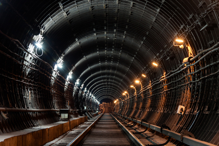 Straight circular subway tunnel with tubing and two different lights: white and yellow.の写真素材