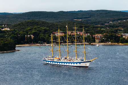 Modern ship with masts and sails similar to the old frigate. Located in the sea on a background of...