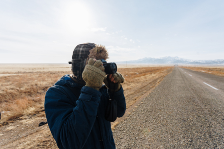 A cheerful traveler with a camera stands on the road in the Kazakh steppe completely alone.の写真素材