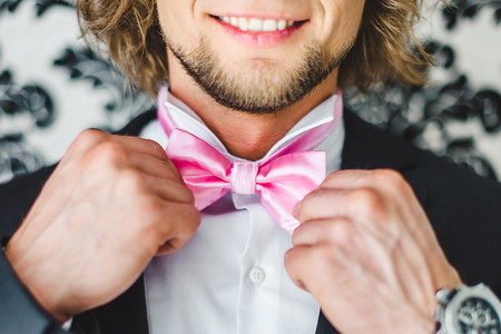 Man the groom in a wedding formal costume with butterfly. Suit, Hands, care, tie, to correct, to adjust, fashion, bow. Instagram colors toningの写真素材
