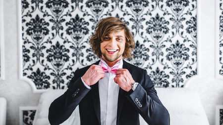 Man the groom in a wedding formal costume with butterfly. Suit, Hands, care, tie, to correct, to adjust, fashion, bow. Instagram colors toningの写真素材