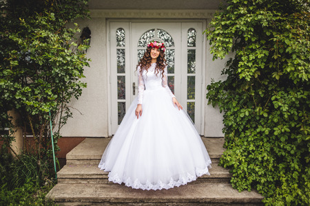 Bride with wreath standing outside in front of a doorの写真素材