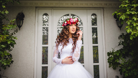 Bride with wreath standing outside in front of a doorの写真素材