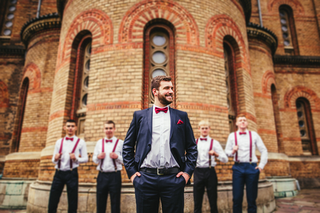 Young groom and his funny friends groomsman posing for camera. Group of young men with bow tie. Cheerful friends. friends outdoors. Wedding day.の写真素材