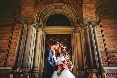 Romantic groom hugging beautiful bride near old big wooden doorsの写真素材