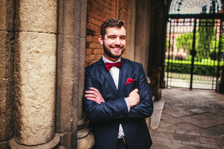 Handsome groom posing near old big columnsの写真素材