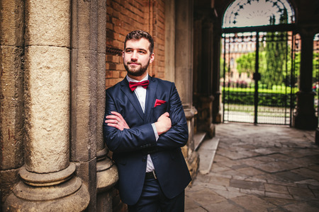 Handsome groom posing near old big columnsの写真素材