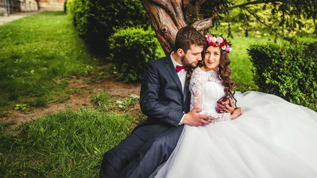 Happy couple, bride & groom hugging near old treeの写真素材