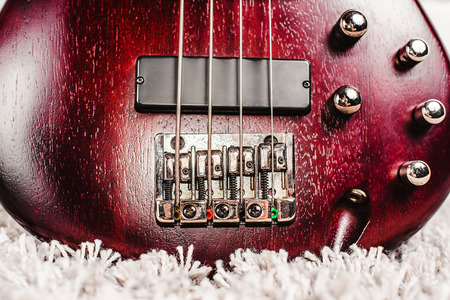 Rosewood bass electric guitar with four strings near the white brick wall closeupの写真素材