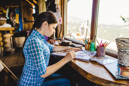 Beautiful young painter in her studio with paints
