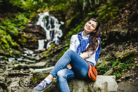 Happy young woman enjoying nature with waterfall in background.の写真素材