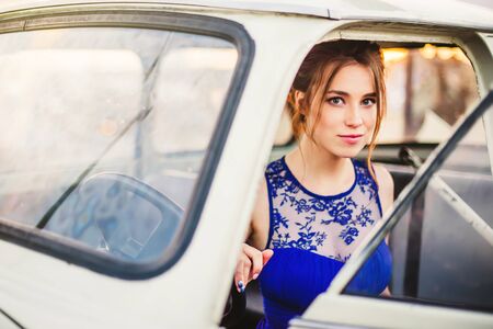 Beautiful girl posing in the white retro car on the roof in the Lviv cityの写真素材