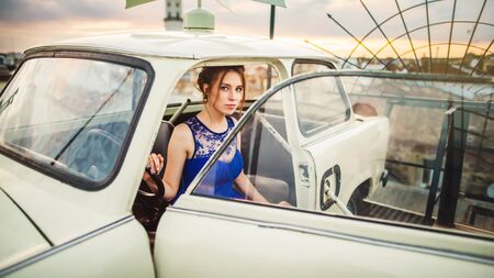 Beautiful girl posing in the white retro car on the roof in the Lviv cityの写真素材