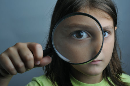 Portrait of a little girl looking through a magnifying glassの写真素材
