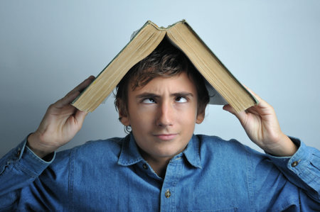 Portrait of a boy holding a heavy book on his head
