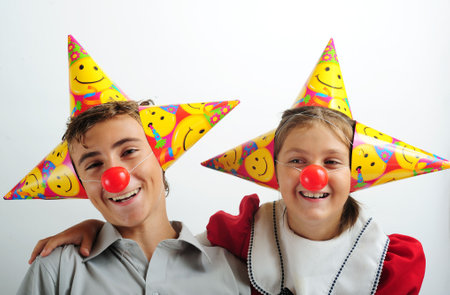 A little girl and a boy with party horn and clown nosesの写真素材