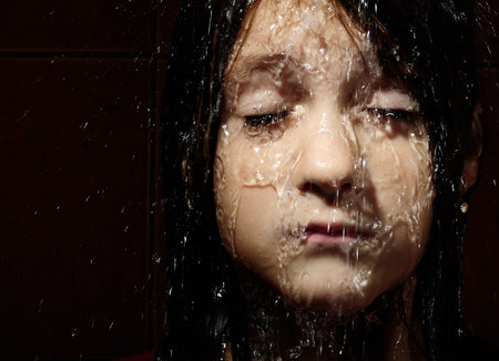 Close up portrait of a girl with water slooping on face