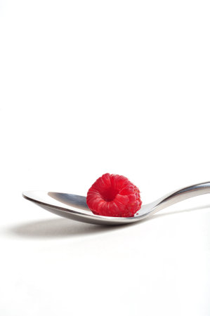 Close up of red raspberry on a spoon, white background