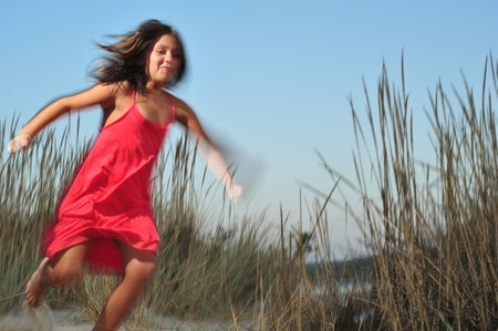 Young girl in red dress running in nature - motion effectの写真素材