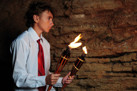 Young businessman lighting with torch in a caveの写真素材