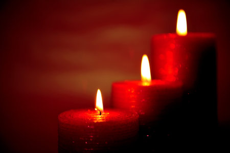 Three burning red candles - selective focus on foregroundの写真素材