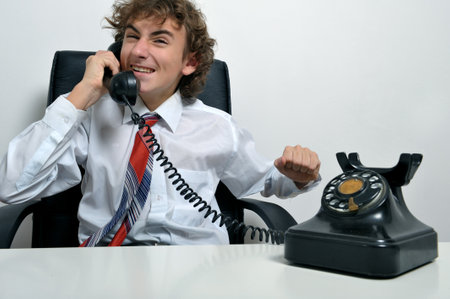 Young business man screaming at an old telephoneの写真素材