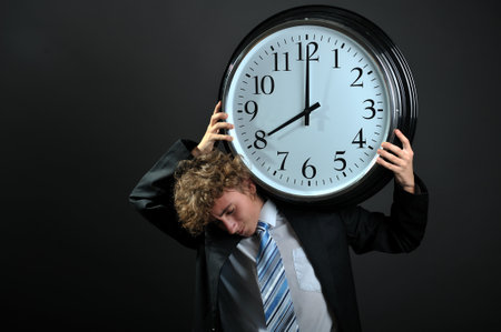 Young businessman holding a big clock on shoulderの写真素材