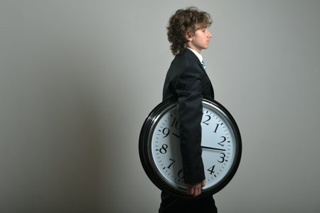 Young businessman holding a big clock in hands, deadline concept
