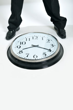 Businessman legs standing next to a big clock の写真素材