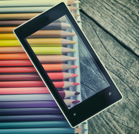 Cell phone  and crayons on wooden table の写真素材