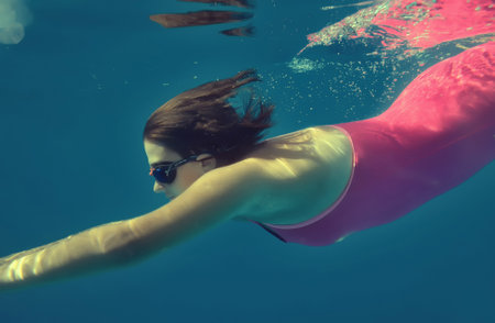 Girl swimming underwater in pool.の写真素材