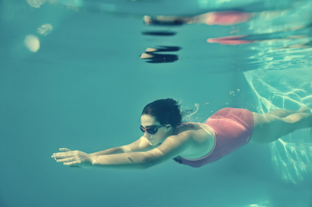 Girl swimming underwater in pool.の写真素材
