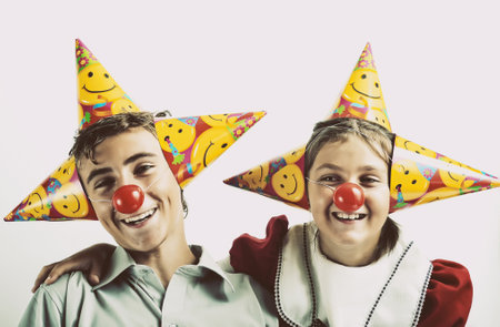 A little girl and a boy with party horn and clown nosesの写真素材