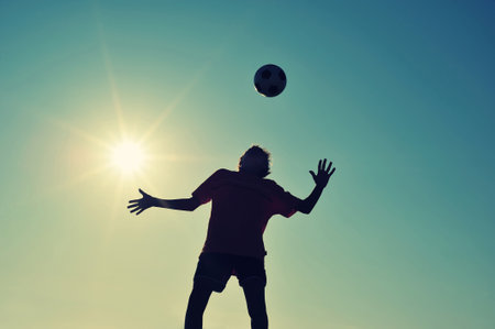 Boy playing football on beach at sunsetの写真素材
